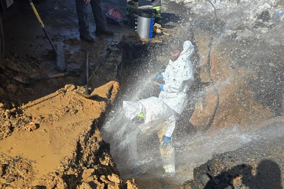 Public Works crews are repairing a break while water sprays them and freezes over the site.