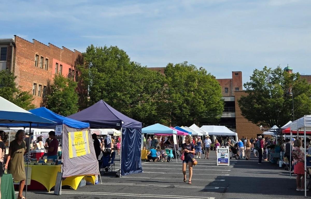 Several tent canopies set up in a parking lot with different vendors.