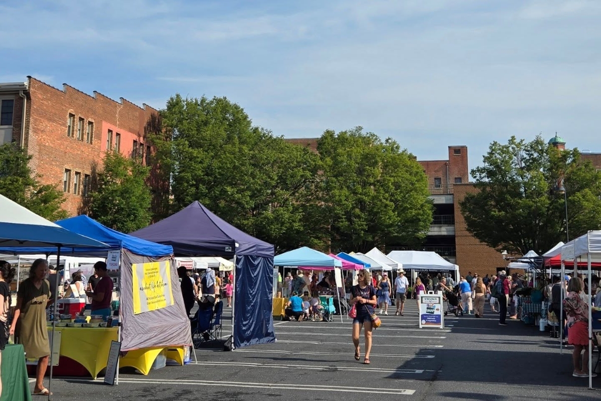 Several tent canopies set up in a parking lot with different vendors.
