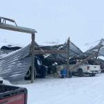 A collapsed barn over trucks.