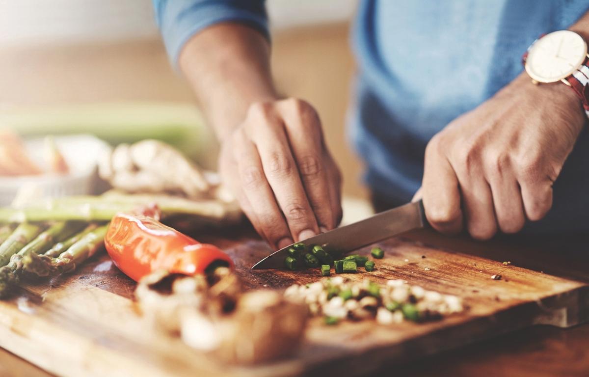 A person chopping vegetables on a cutting board.