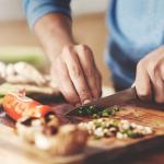 A person chopping vegetables on a cutting board.