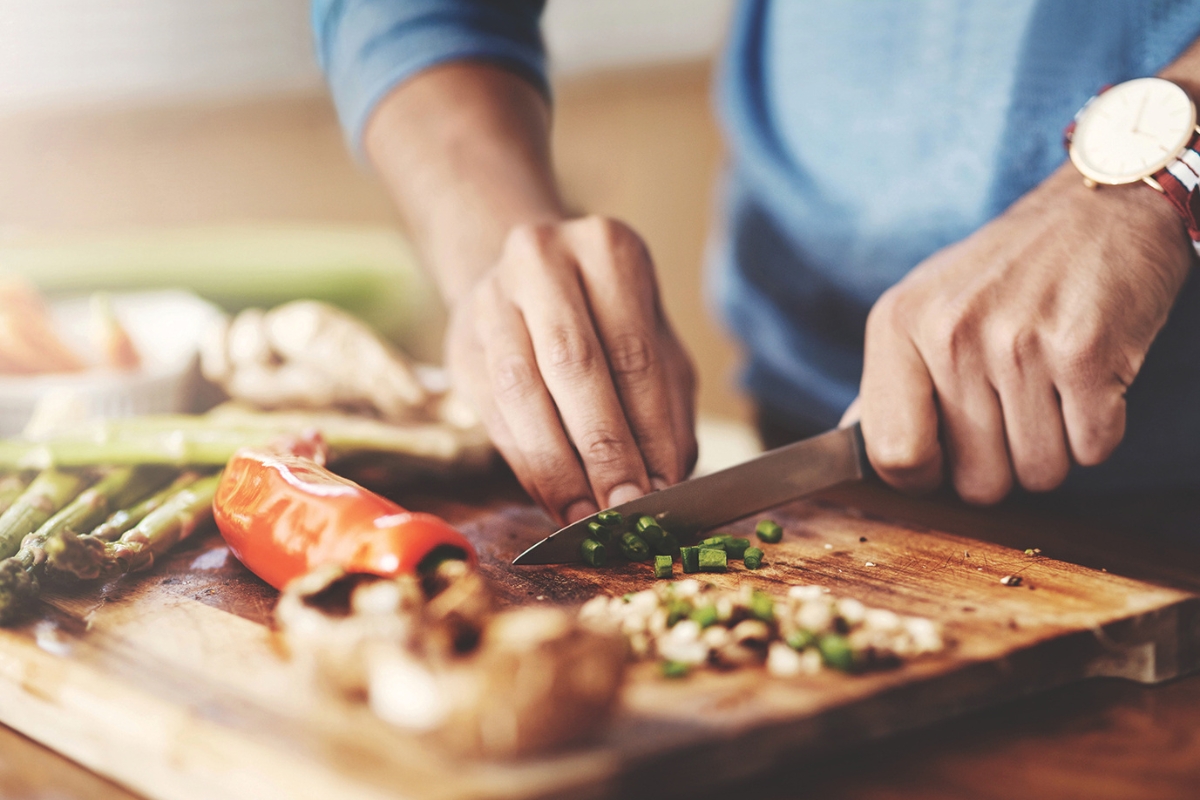 A person chopping vegetables on a cutting board.