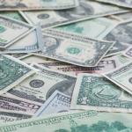 Lots of individual paper money bills laying on a table.