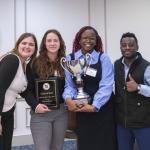 Ifeatu Udokwu, Laine Anthony, Madison Lizarraga, and Isaac Plange holding a plaque and trophy.