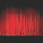 Red curtains drawn together on a stage with a spotlight.