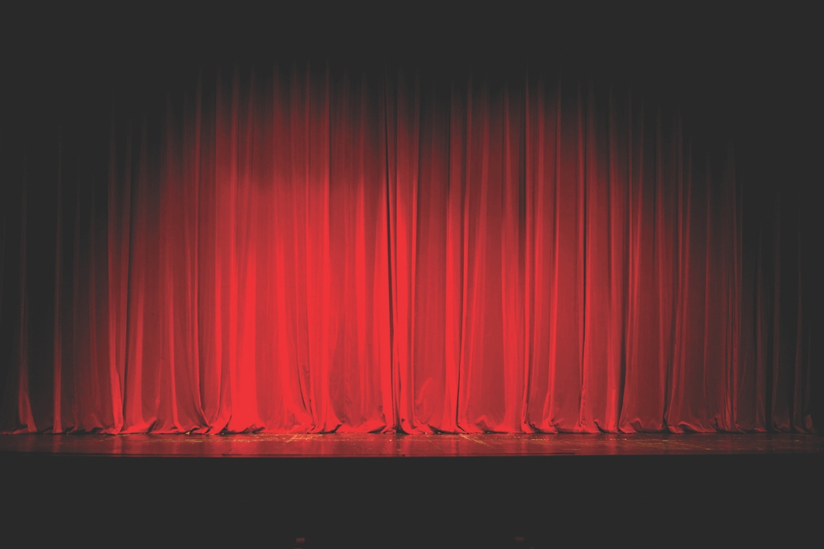 Red curtains drawn together on a stage with a spotlight.