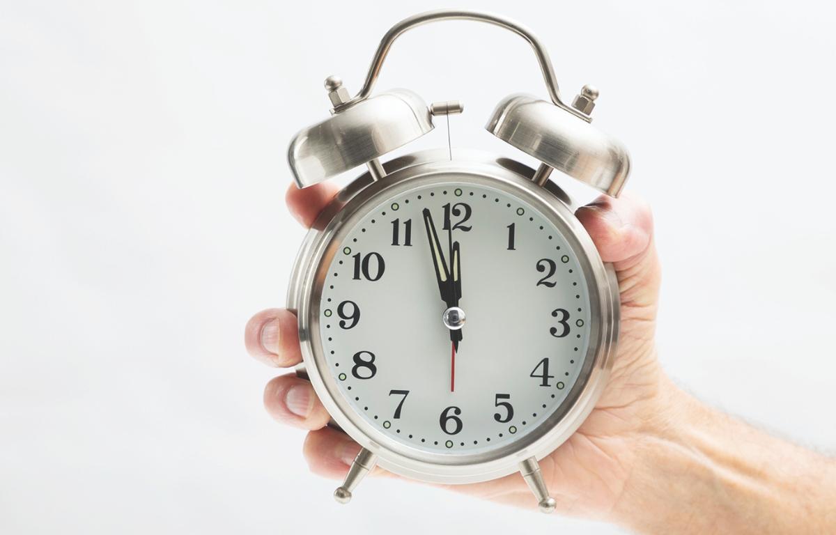 A hand holding an alarm clock.