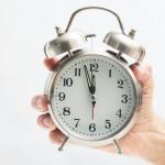 A hand holding an alarm clock.