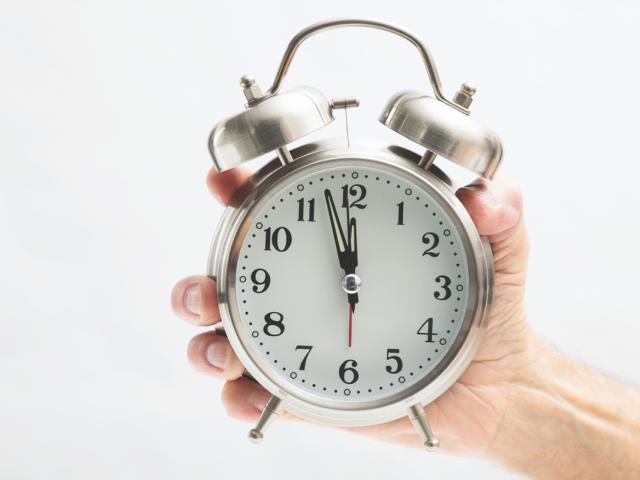 A hand holding an alarm clock.