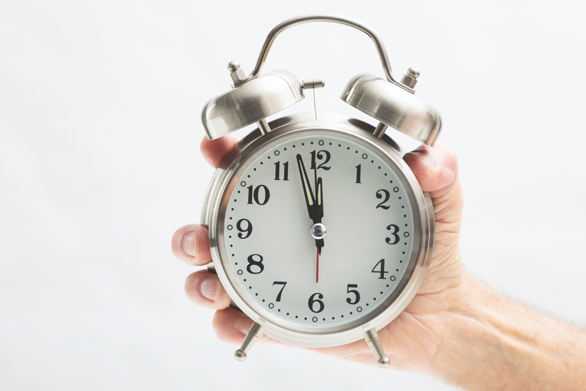 A hand holding an alarm clock.