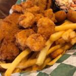 Plate of golden fried chicken pieces with crispy fries and a side of coleslaw in a basket.