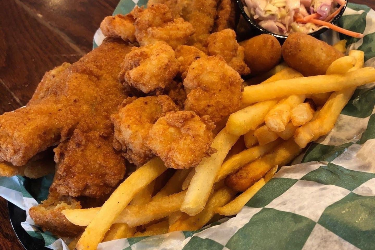 Plate of golden fried chicken pieces with crispy fries and a side of coleslaw in a basket.