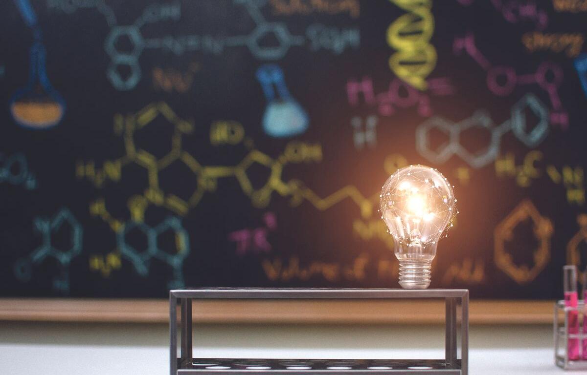Lightbulb in front of a chalkboard