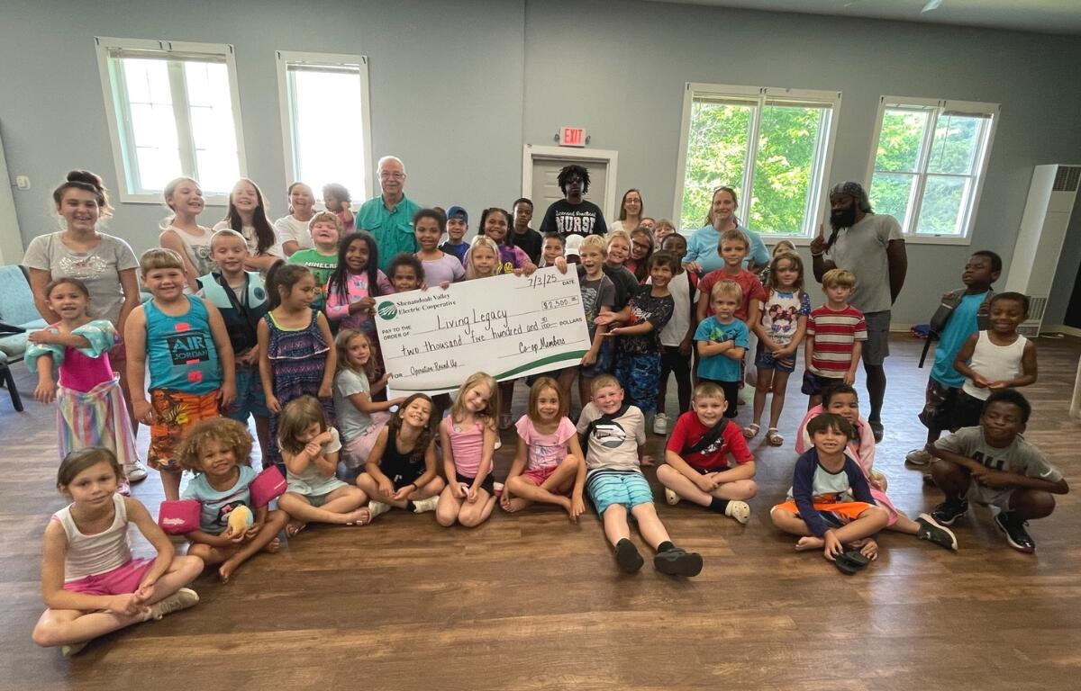A classroom of children at Living Legacy holding a giant check.