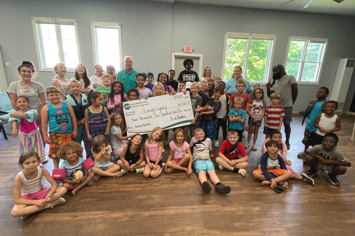 A classroom of children at Living Legacy holding a giant check.