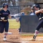 Bridgewater College softball: batter swinging at a pitch as a teammate runs toward home, with a large B logo in the corner.