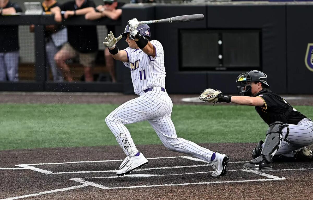Baseball batter in white pinstripe uniform swings at a pitch as the catcher in black crouches behind home plate during a game in progress.