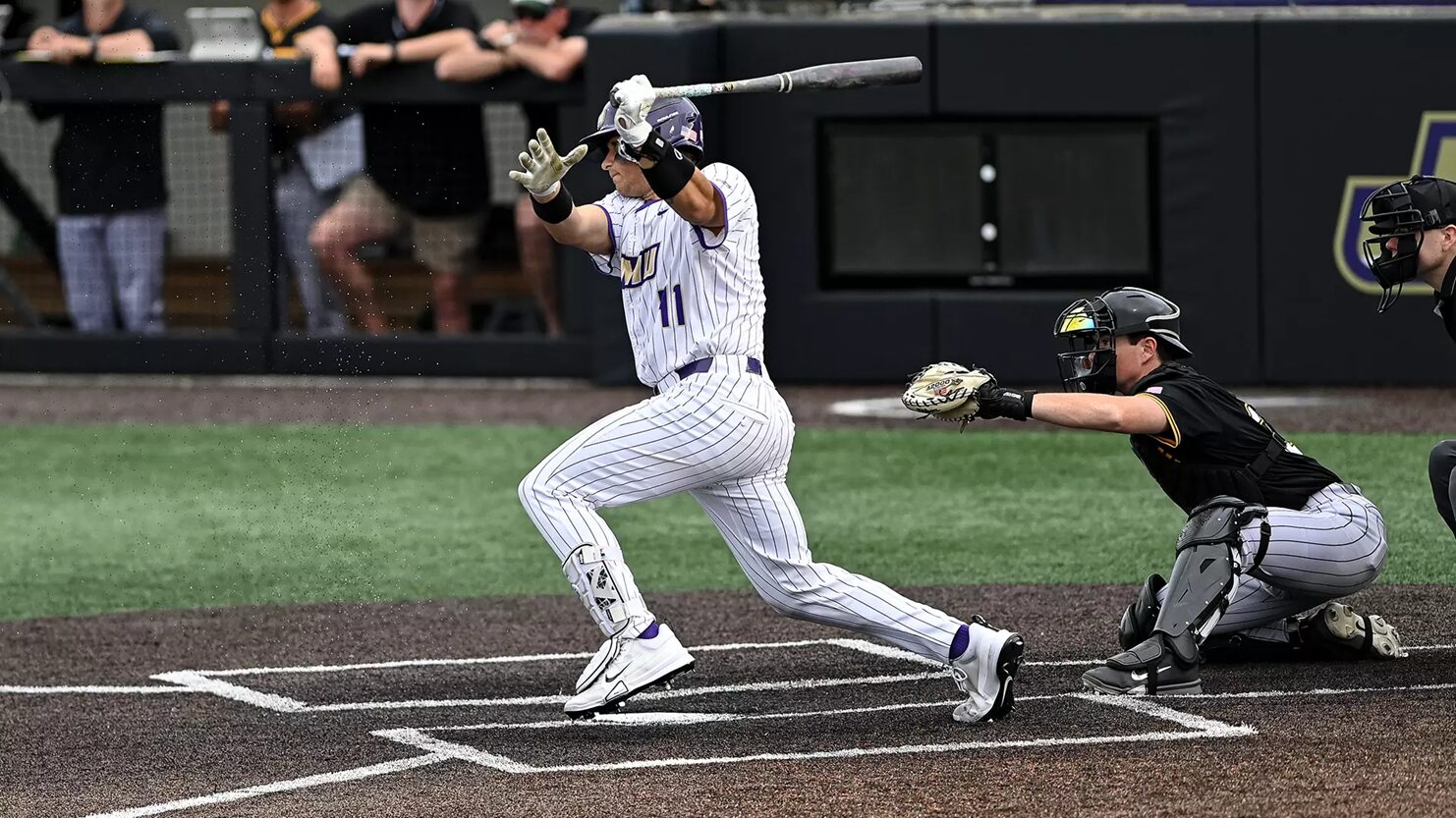 Baseball batter in white pinstripe uniform swings at a pitch as the catcher in black crouches behind home plate during a game in progress.