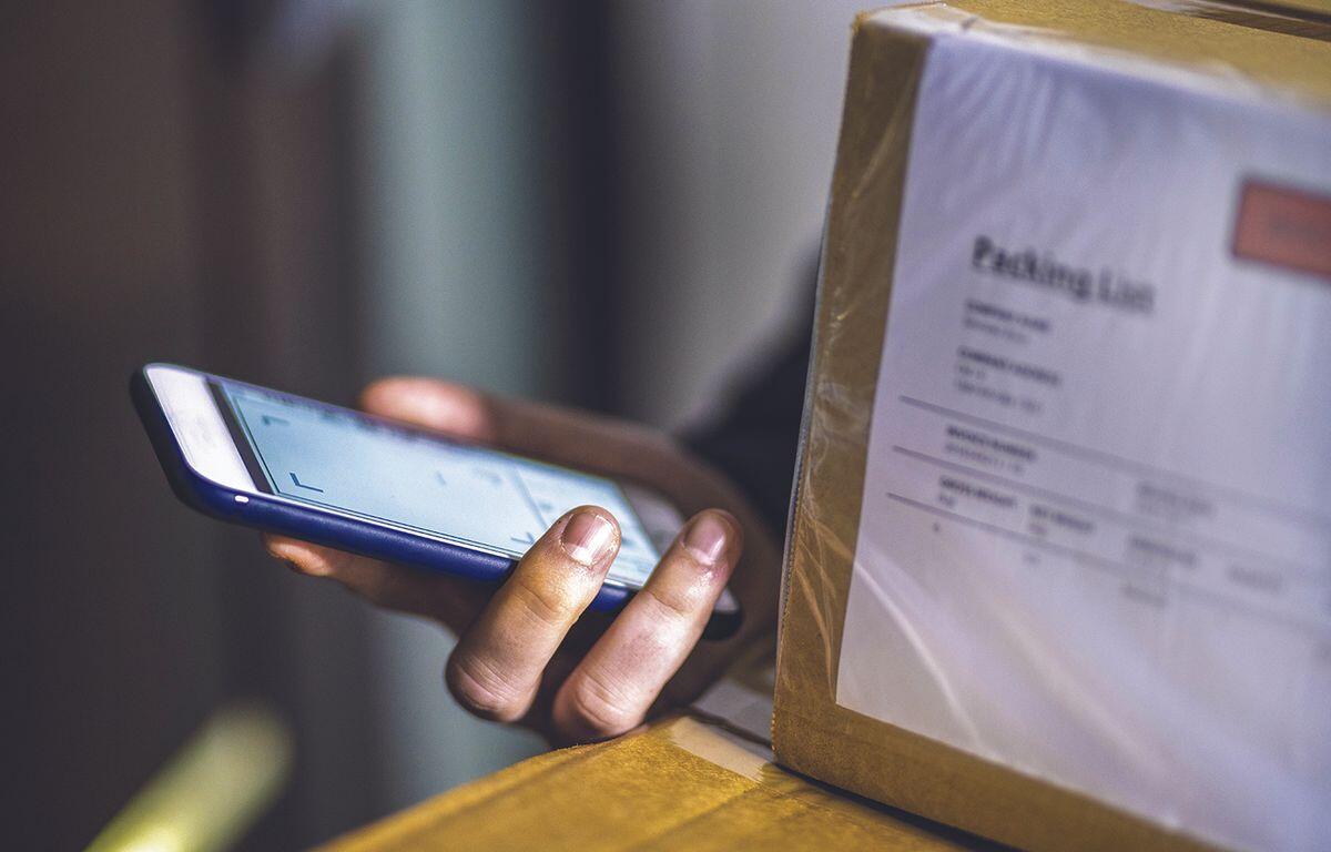 Person holding a cell phone and packages