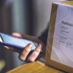 Person holding a cell phone and packages