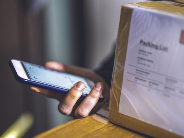 Person holding a cell phone and packages