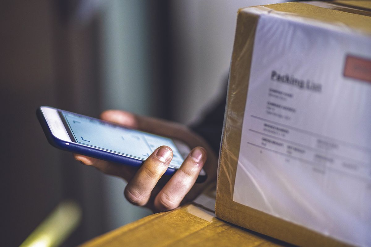 Person holding a cell phone and packages
