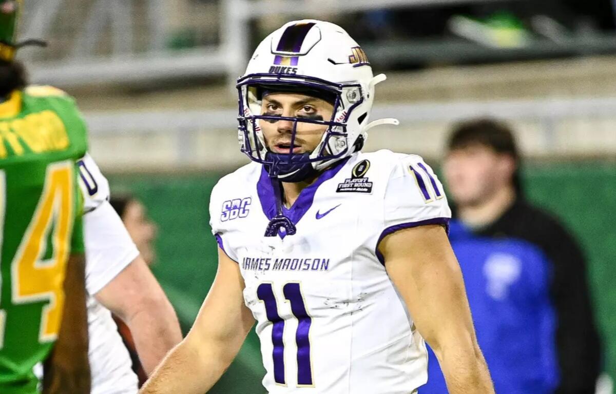 James Madison football player in a white jersey #11 with purple trim and helmet, during a game.