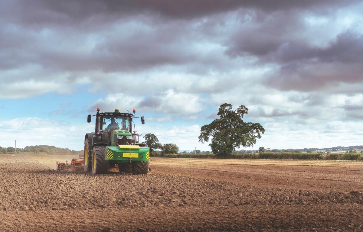 A tractor plows a dirt field