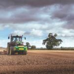 A tractor plows a dirt field