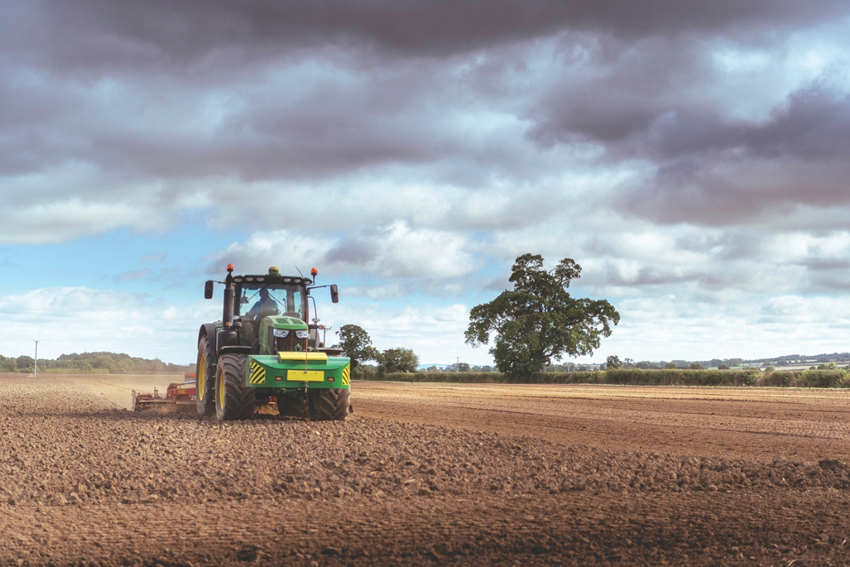 A tractor plows a dirt field