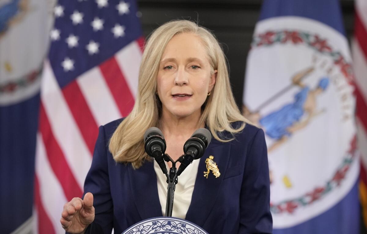 Abigail Spanberger stands in front of a United States flag and Virginia flag.