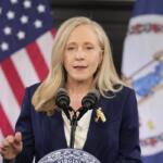 Abigail Spanberger stands in front of a United States flag and Virginia flag.
