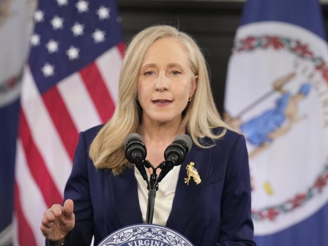 Abigail Spanberger stands in front of a United States flag and Virginia flag.