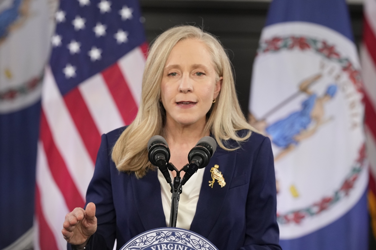 Abigail Spanberger stands in front of a United States flag and Virginia flag.