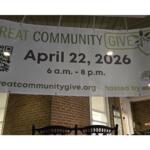 Banner promoting 'Great Community Give' on a brick porch displaying April 22, 2026 and a QR code.