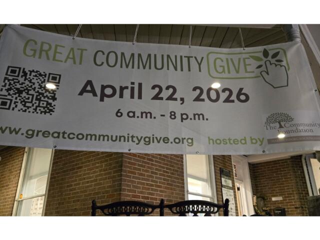 Banner promoting 'Great Community Give' on a brick porch displaying April 22, 2026 and a QR code.