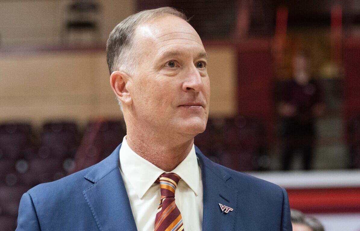 Professional portrait of a middle-aged man in a blue suit and striped tie, wearing a VT pin, looking to the right in an indoor venue.