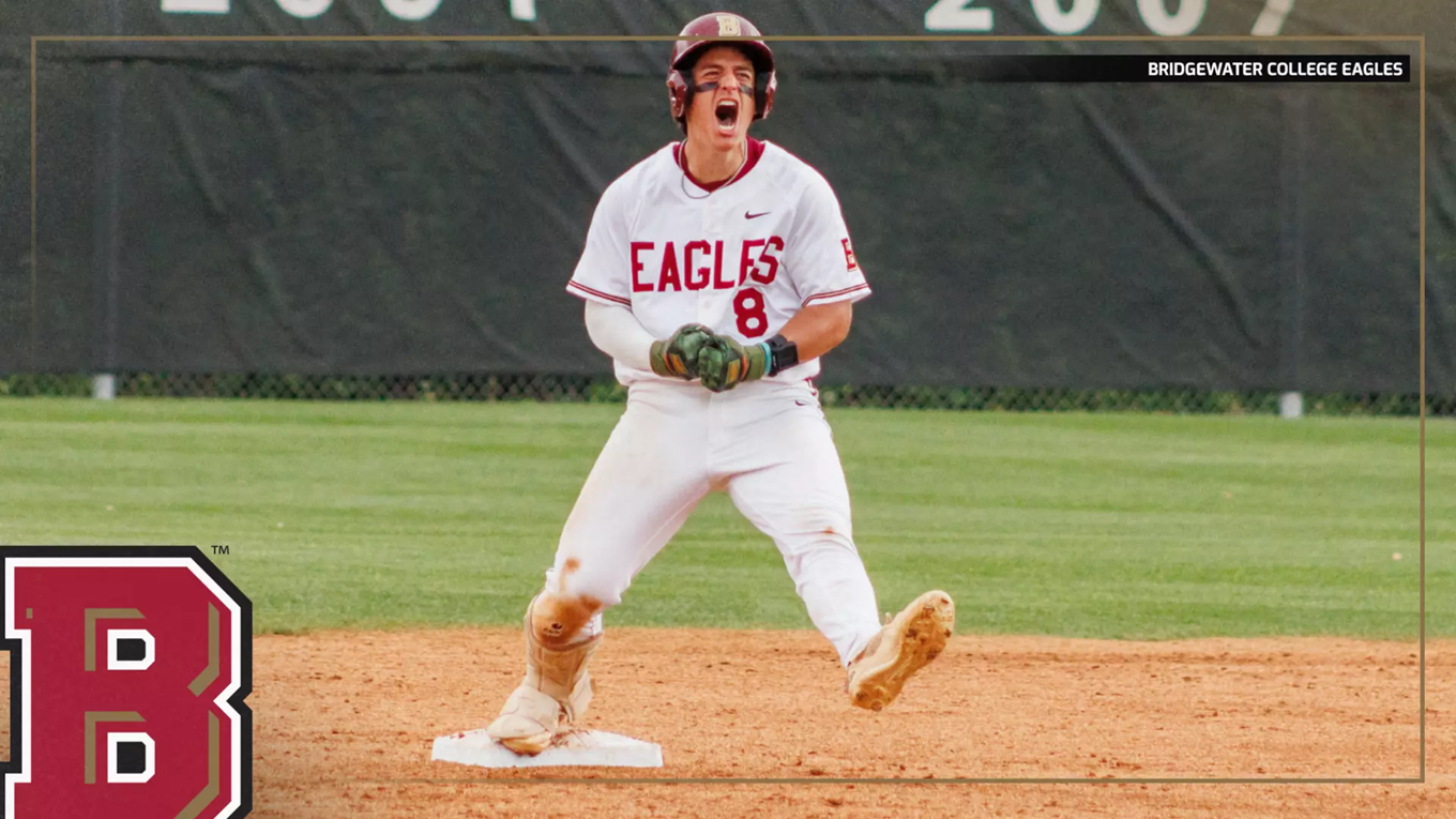 Baseball player in a white Eagles uniform slides into first base on the dirt infield, with a large team logo in the foreground and a green outfield behind him.