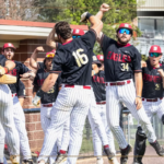 Bridgewater College Eagles baseball team celebrating a win with high-fives at the dugout, players in black jerseys and white pinstriped pants.