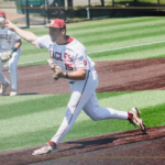 Bridgewater College Eagles pitcher on the mound delivering a pitch during a game; teammate in the background; school logo bottom left.