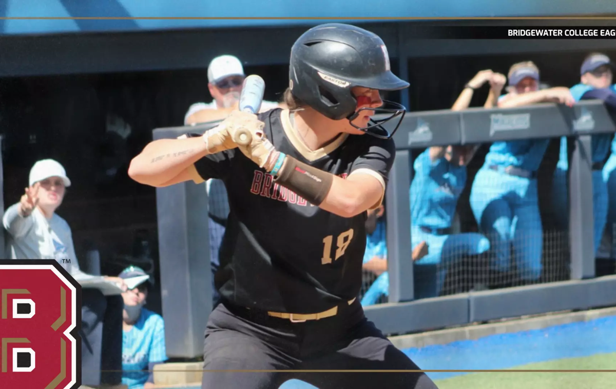 Baseball player in black uniform swinging a bat during a game, Bridgewater College Eagles on the jersey, crowd in the background.