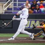 Baseball batter in white pinstripe uniform (-number 37) swings at a pitch as the catcher in yellow crouches behind home plate with an umpire nearby.