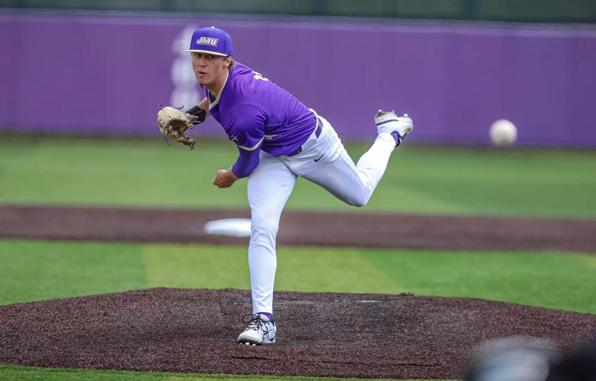 College baseball pitcher in purple uniform throwing from the mound, ball in midair behind him.