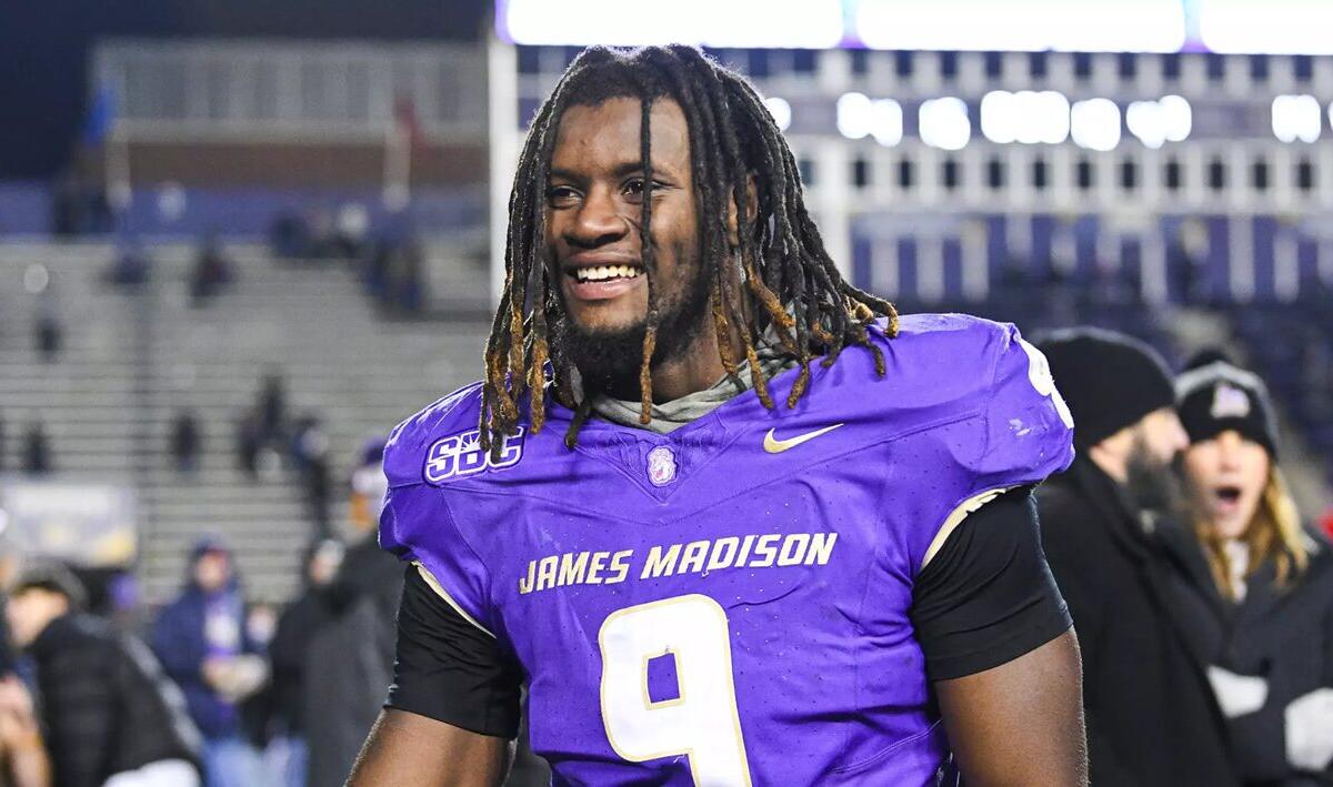 Football player in purple jersey with number 9, smiling on the field after a game.