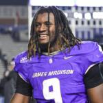 Football player in purple jersey with number 9, smiling on the field after a game.