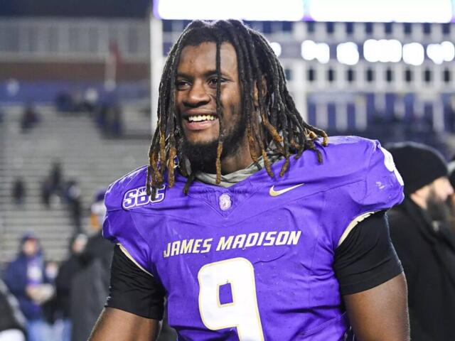 Football player in purple jersey with number 9, smiling on the field after a game.