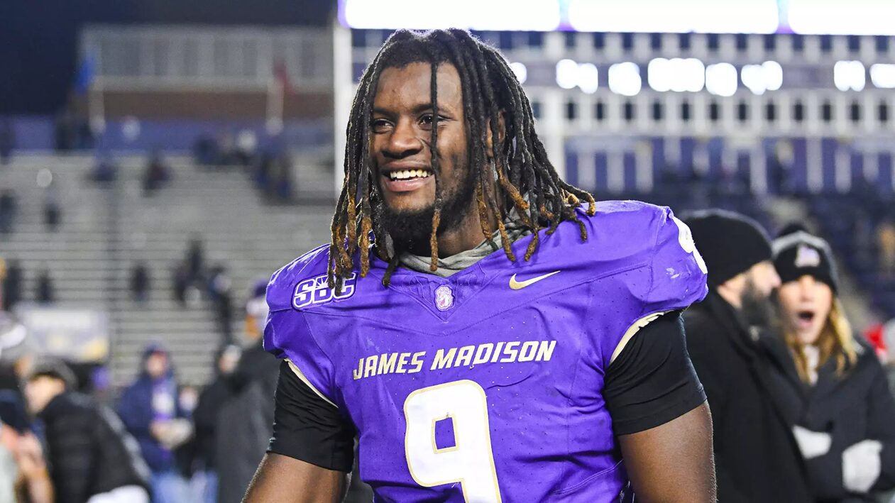 Football player in purple jersey with number 9, smiling on the field after a game.