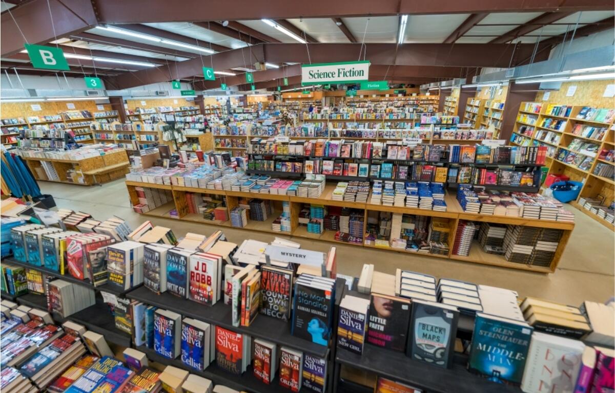 Inside a large bookstore with a central display of stacked science fiction books and a 'Science Fiction' sign overhead.