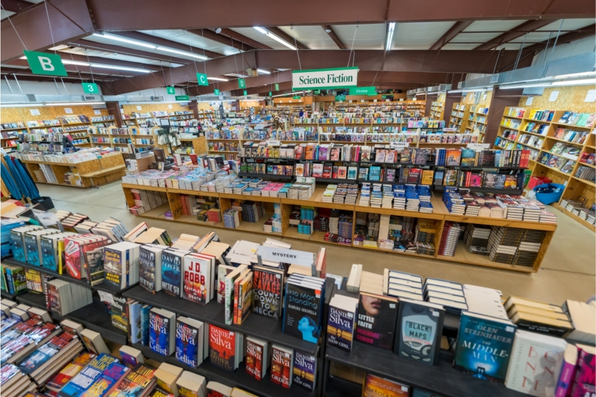Inside a large bookstore with a central display of stacked science fiction books and a 'Science Fiction' sign overhead.